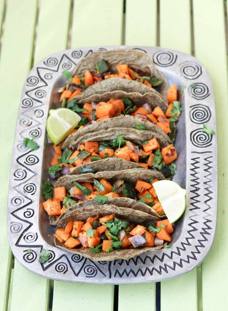 sweet potato tacos closeup on a southwestern style metal platter on a green table