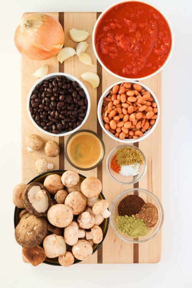 cutting board with black and pinto beans, tomatoes, onion, garlic, mushrooms, black coffee and seasonings.