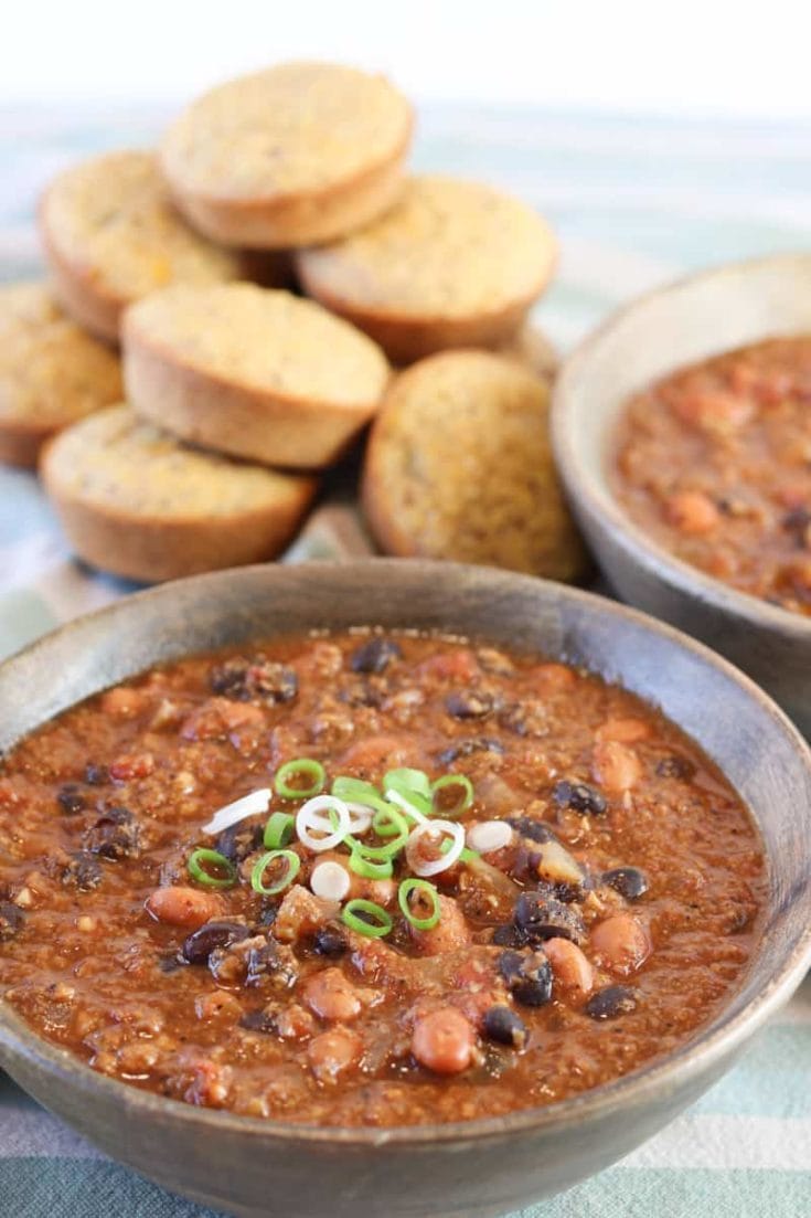 Best damn Vegan Chili in a wooden bowl with polenta muffins on a green striped towel