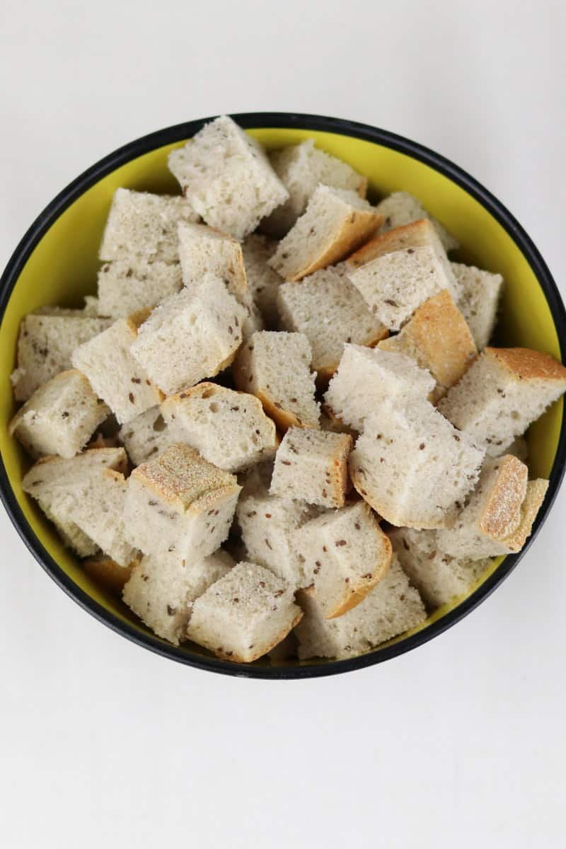 light rye bread cubes in a yellow bowl with a black rim.