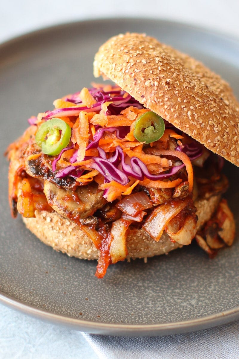 Oven-Roasted BBQ Mushroom Sandwich with Purple cabbage carrot and jalapeño slaw on a gray plate