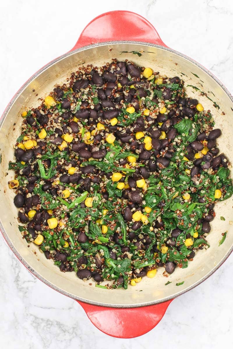 black beans, quinoa, spinach and corn in a red dutch oven