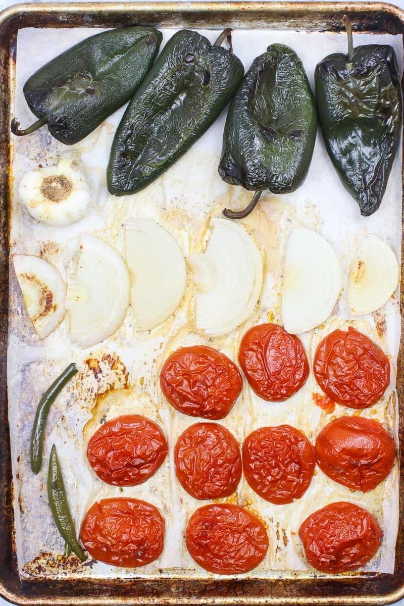 poblano peppers, onions, garlic, tomatoes and Serrano peppers on a sheet pan