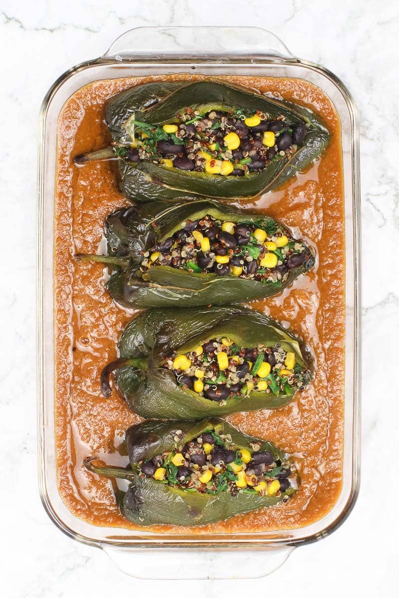 vegan chile relleno in red sauce in a clear baking dish