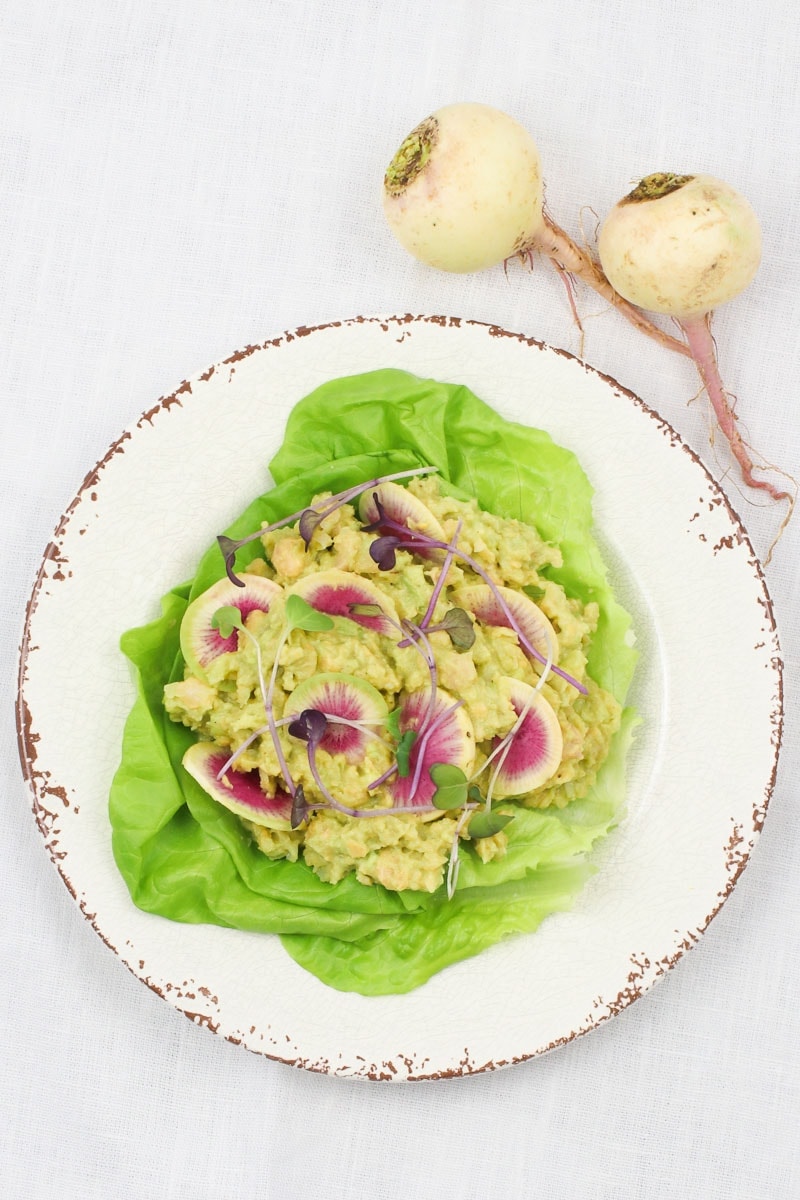 vegan egg salad on bib lettuce leaves with beauty heart radishes and micro greens on a plate