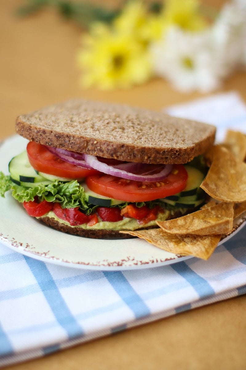 Mediterranean sandwich on a plate with tortilla chips plaid napkin and daisies