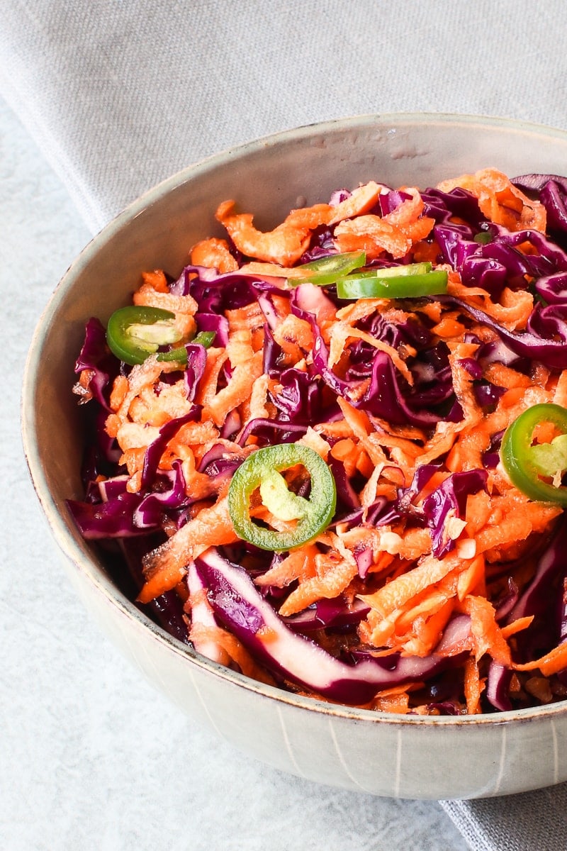 close up of a bowl of purple cabbage slaw with carrots and jalapeños