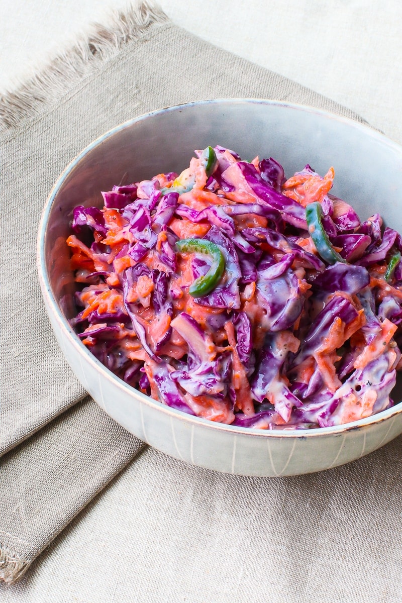 bowl of creamy purple cabbage slaw with carrots and jalapeños 