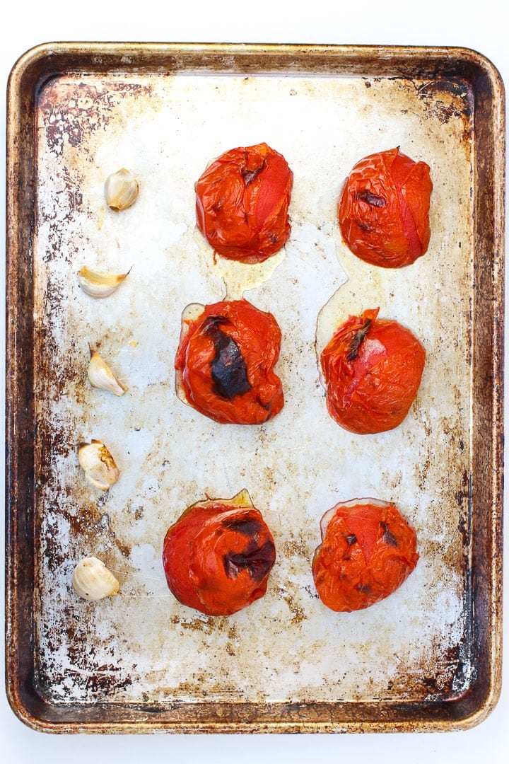 charred tomatoes and garlic on a sheet pan