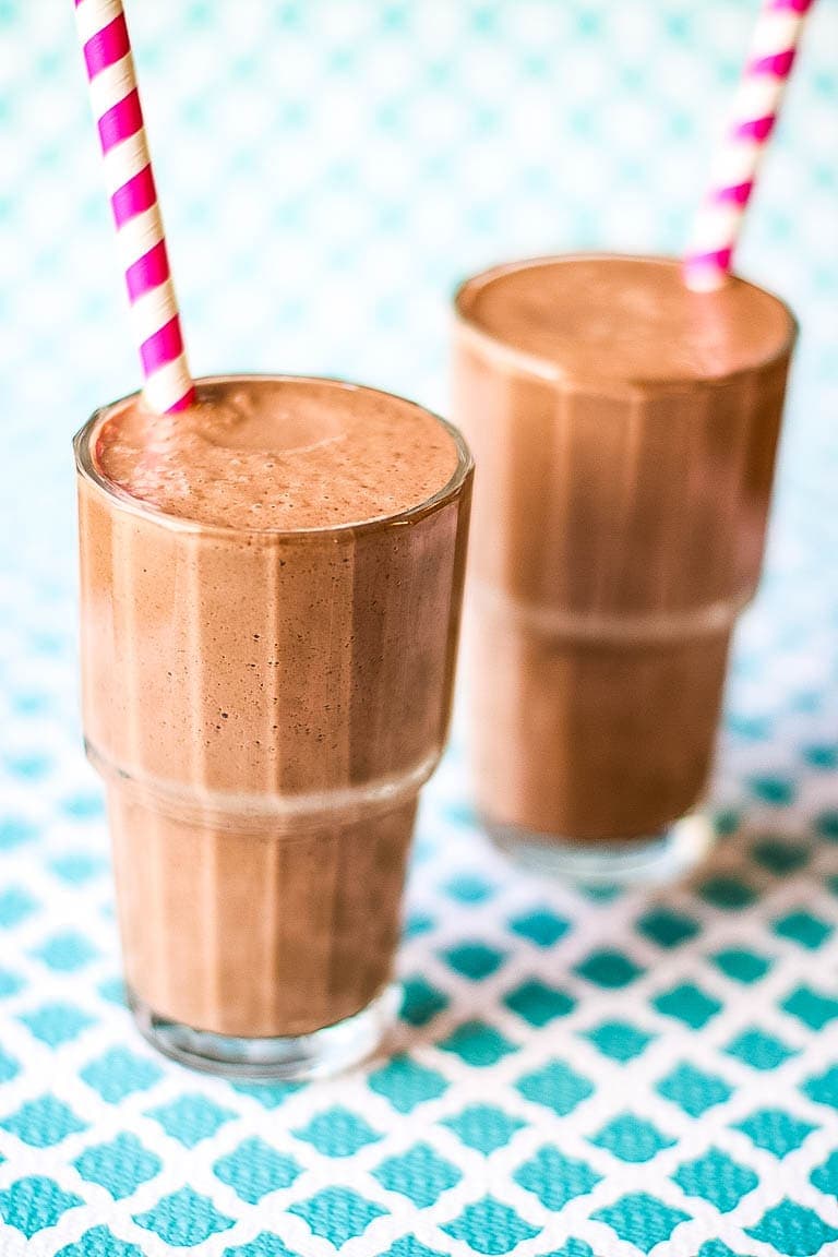 Two glasses of smoothies with straws.