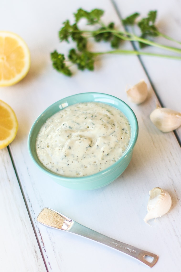 of Oil Free Dairy Free Ranch Dressing in pale blue bowl with lemons, parsley garlic 
