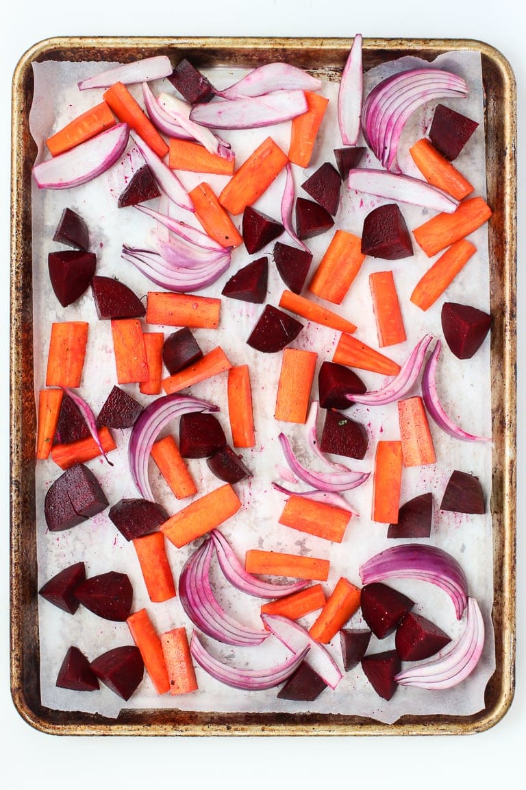 Baking sheet with parchment paper and carrots, beets and red onion