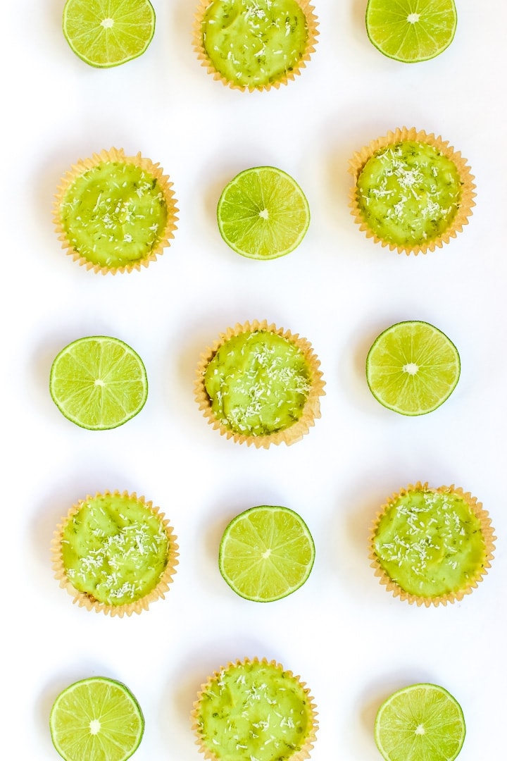 overhead shot of vegan key lime pie mini tarts and cut limes on a white background