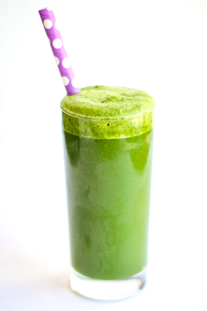 Green smoothie with ginger, in a tall class with a purple polka dot straw