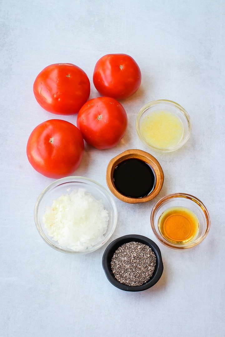 tomatoes, lemon, maple syrup, shallot, garlic, balsamic vinegar and chia seeds on a gray background.