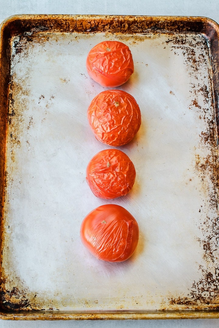 4 Tomatoes with wrinkled skins on a sheet pan.