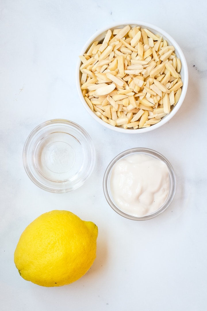 almond ricotta ingredients--soaked almonds, non-dairy yogurt and lemon on marble.