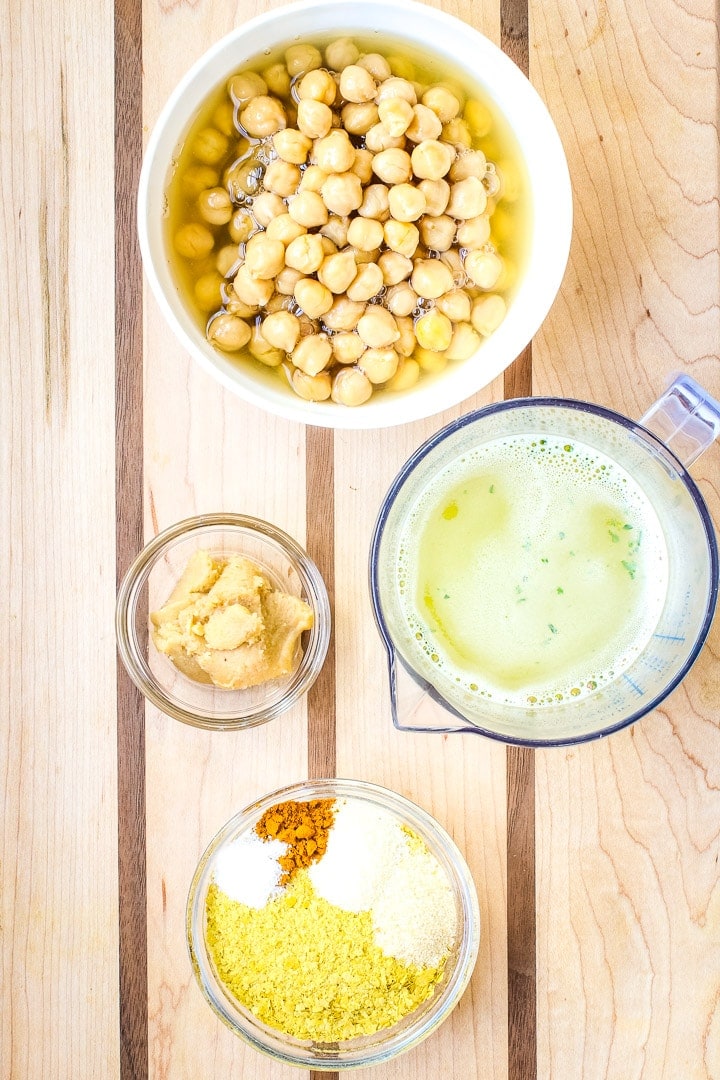 Chickpea Cheese Sauce ingredients on a cutting board: chickpeas, veggie broth, miso paste, nutritional yeast, seasonings.