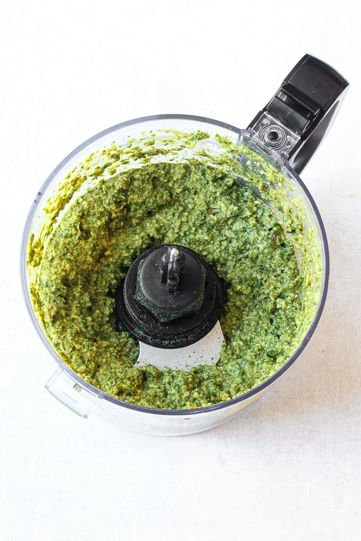 Pesto in a food processor on white.