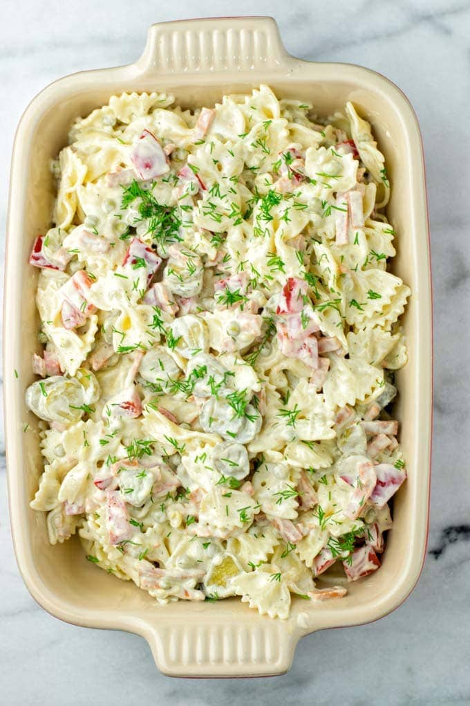 Bowtie pasta salad with dill in a rectangular baking dish on marble.