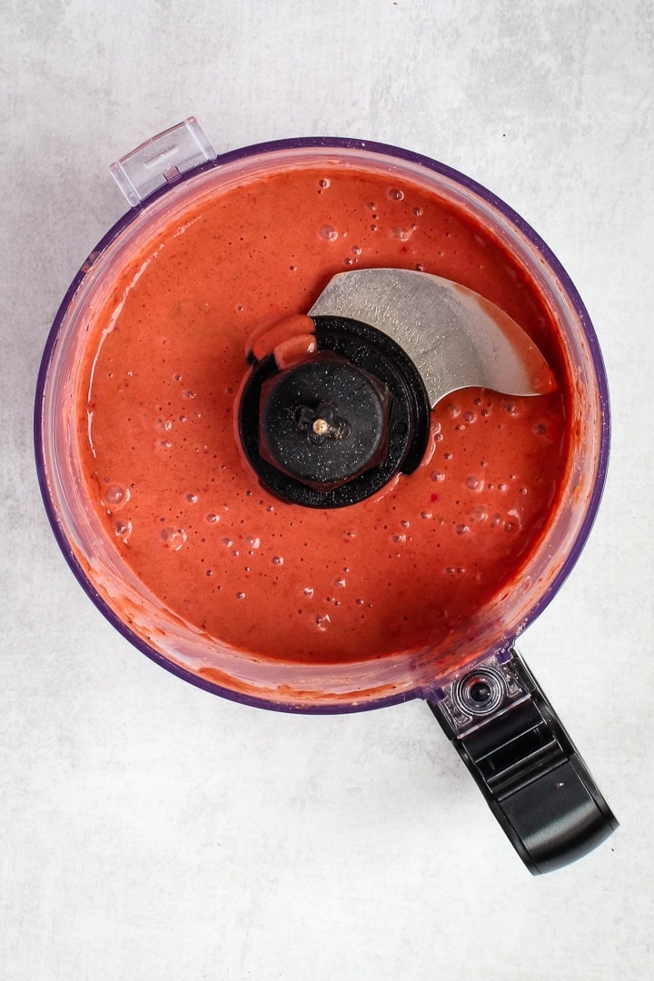 Strawberry balsamic vinaigrette in a food processor bowl on gray background.