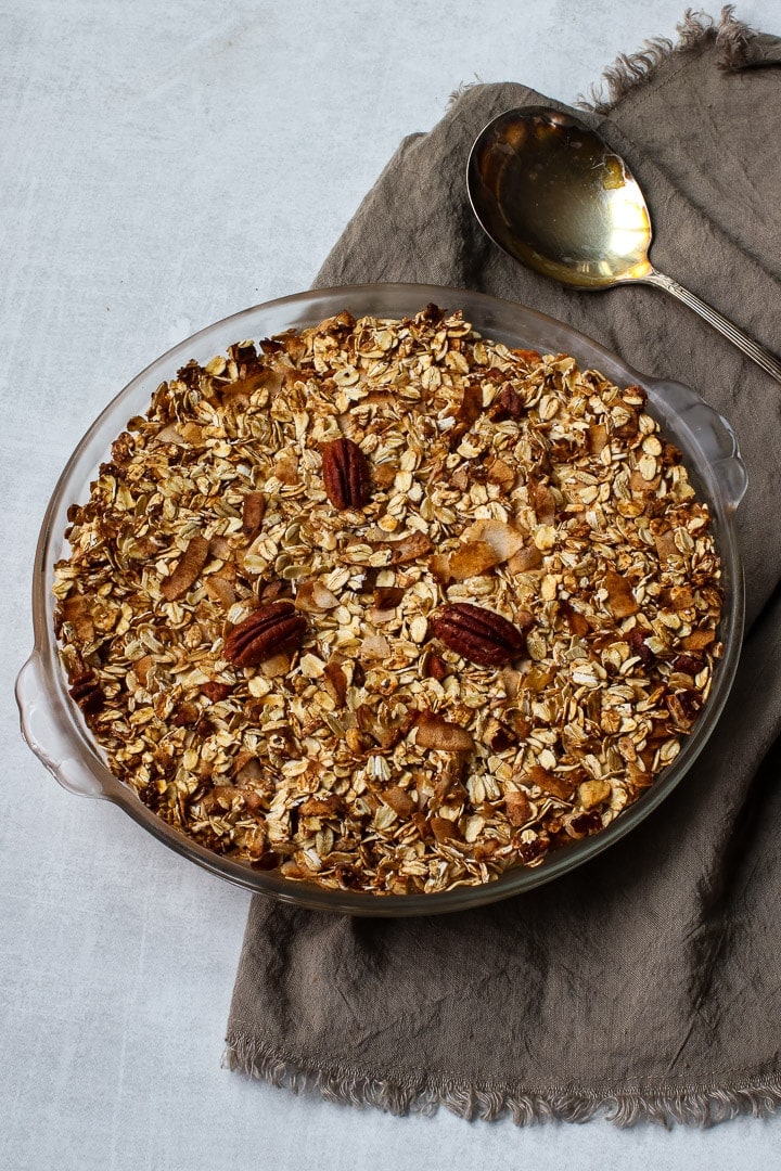 Sweet potato casserole in clear glass pie dish on brown napkin with antique spoon.