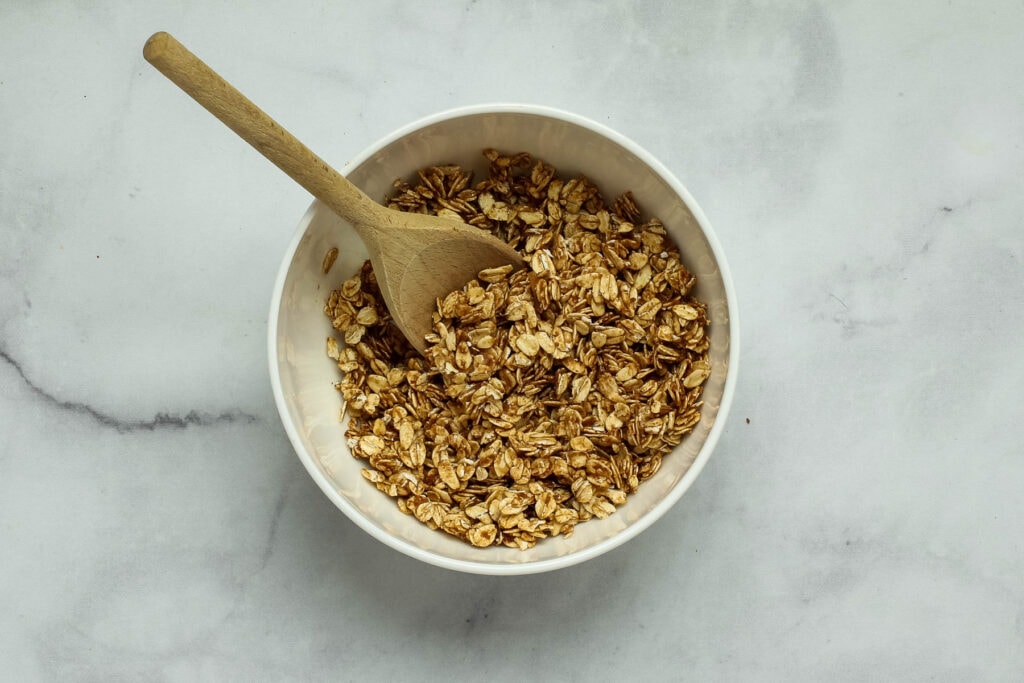 Tossing the oats, cinnamon and date paste in a mixing bowl.