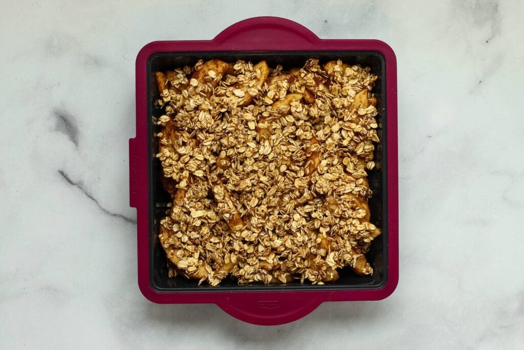 Apple crisp in a silicone baking dish on white marble.