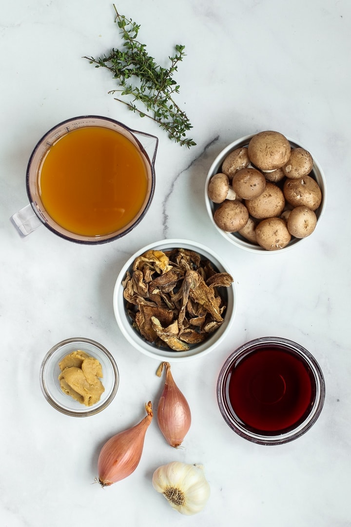 vegan mushroom gravy ingredients: vegetable stock, fresh thyme, dried porcini mushrooms, red wine, shallots, miso paste, garlic, optional cremini mushrooms.