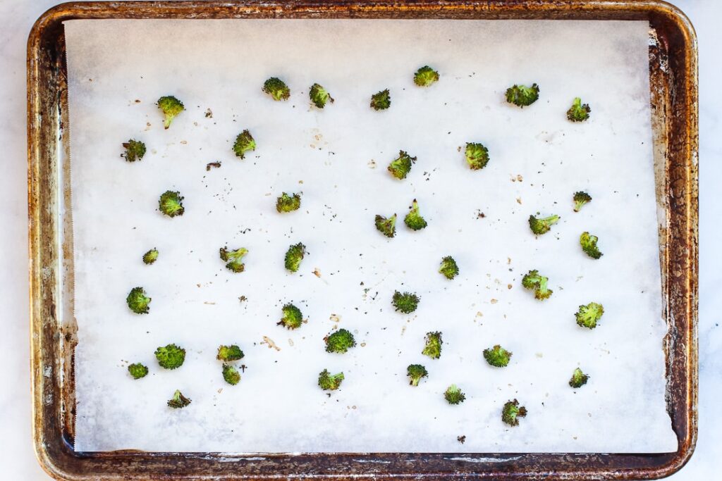Broccoli Croutons Broccoli florets roasted on a baking sheet with parchment paper.