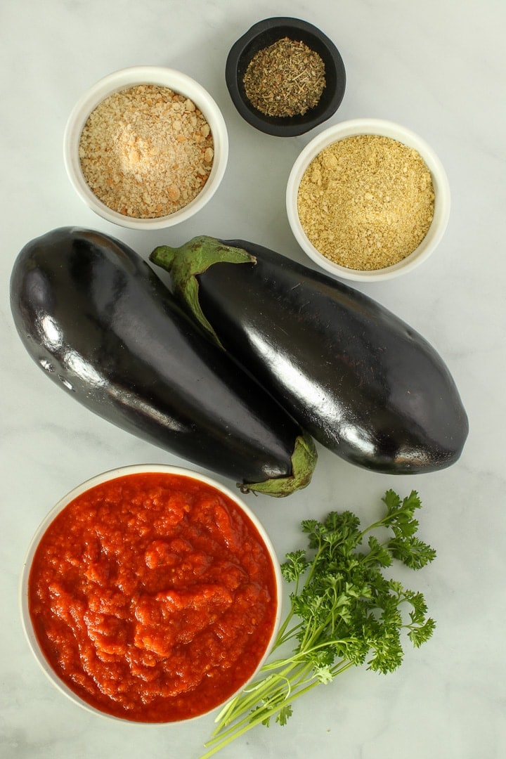 Vegan Eggplant Parmesan ingredients: Eggplants, tomato sauce, panko bread crumbs, vegan Parmesan, Italian Seasonings, optional fresh parsley.