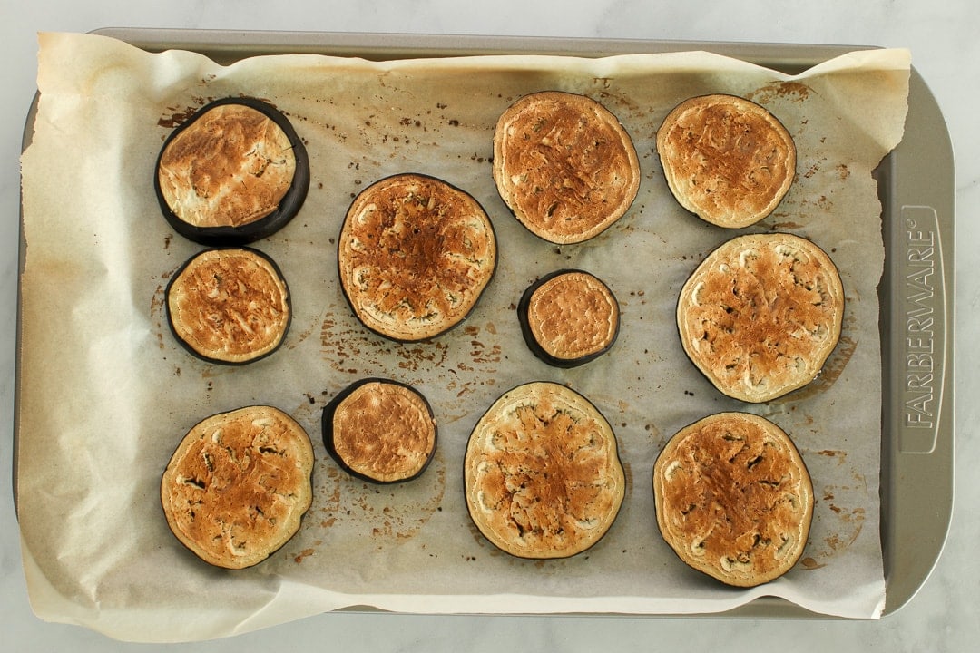 roasted eggplant slices Roasted eggplant slices on a parchment paper lined baking sheet.