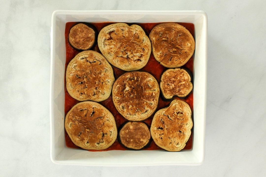eggplant slices over tomato sauce Layer roasted eggplant slices over the tomato sauce.