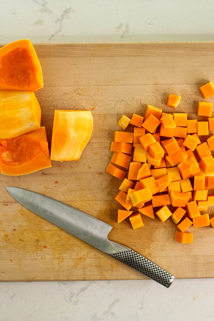 diced squash and segments on wood cutting board with knife