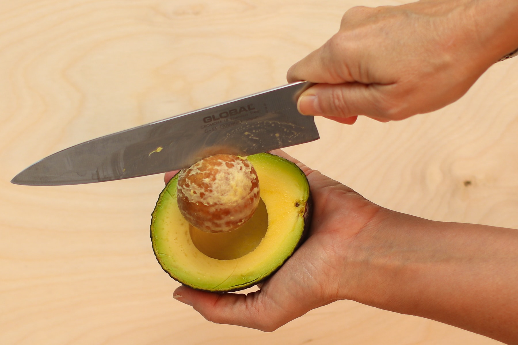 I'm holding a knife, the blade of which isinserted into an avocado, and pulling the pit out. 