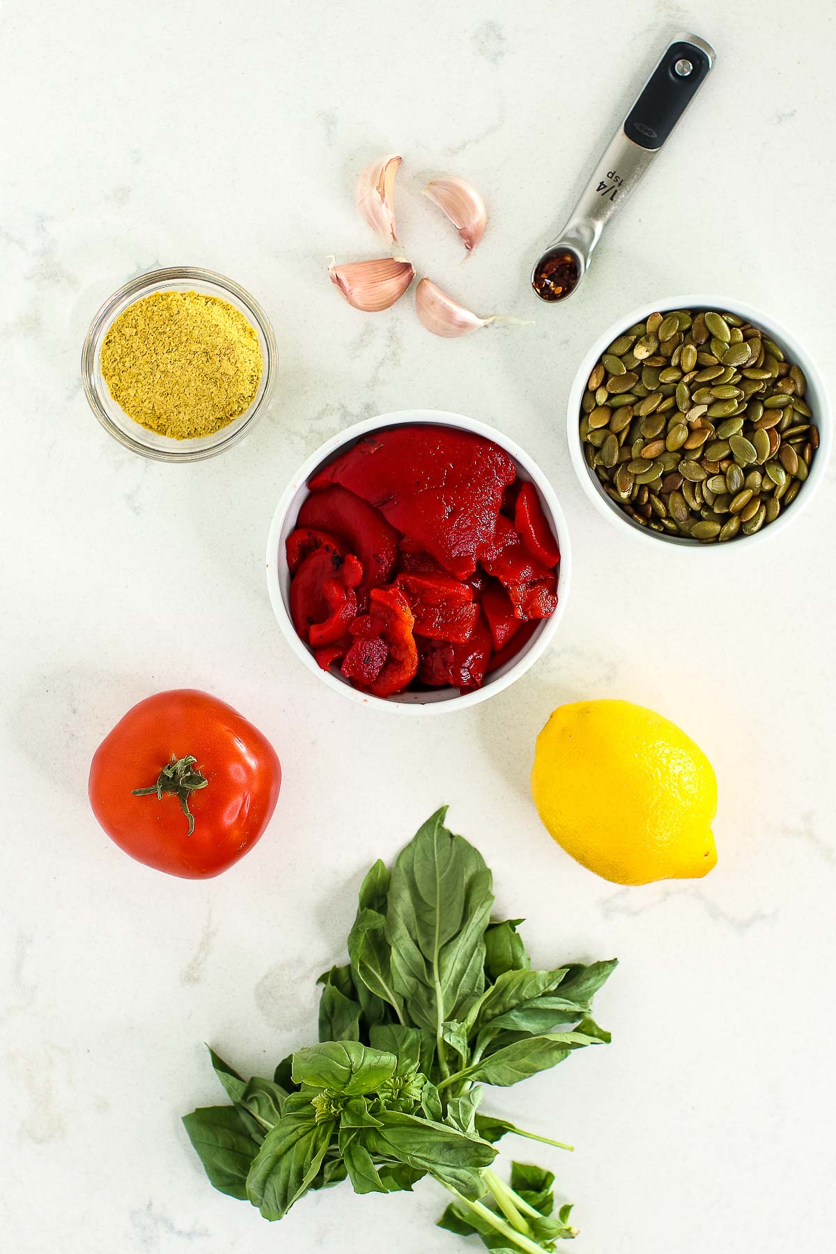 Ingredients (roasted red peppers, tomato, basil, garlic, lemon, etc) on marble