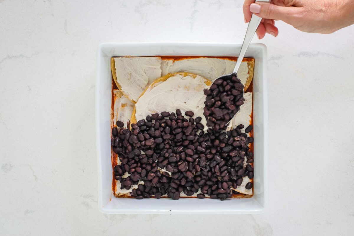 spooning black beans into the dish