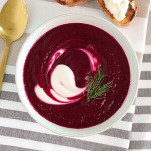 Beet soup bowl with spoon and baguette slices.