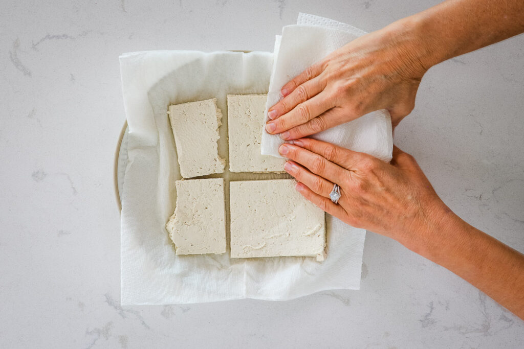 Pressing tofu by hand with paper towels. 