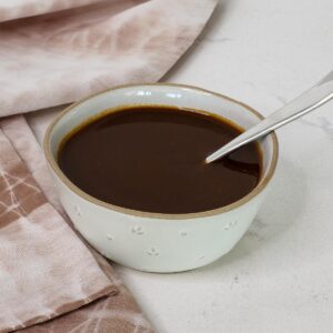 Bowl of soy sauce with spoon and towel.