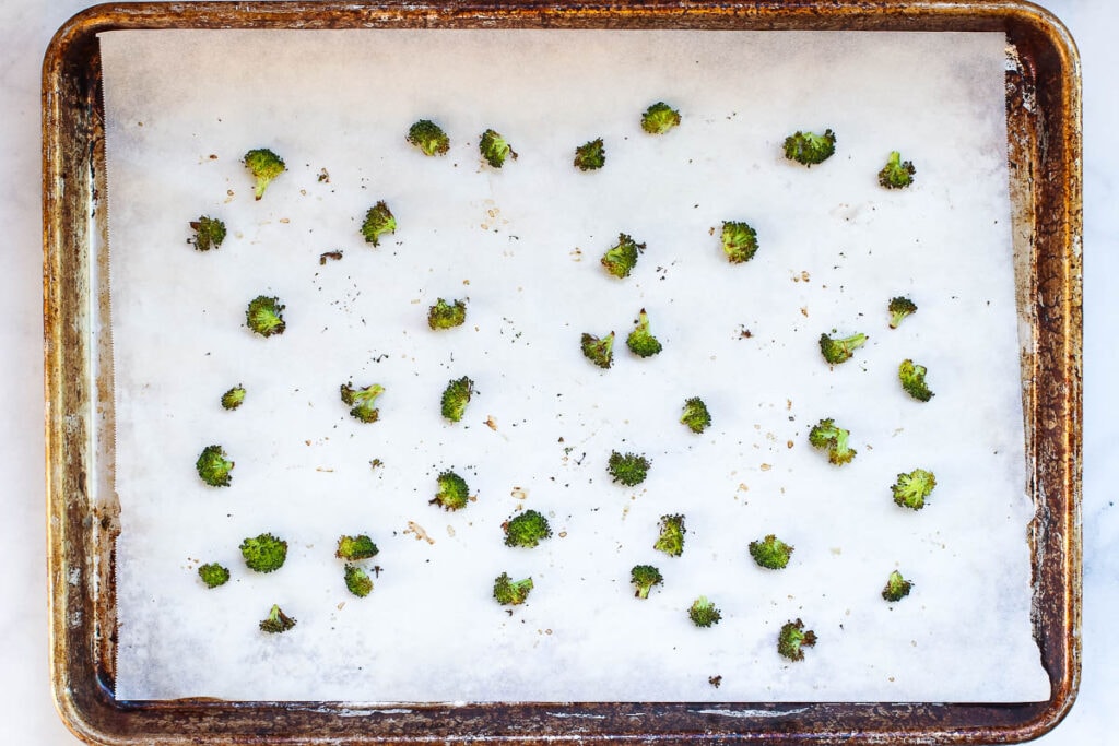 Small roasted broccoli florets on a sheet pan.