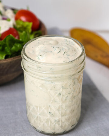 Oil free vegan ranch dressing in a mason jar with salad and spoon.