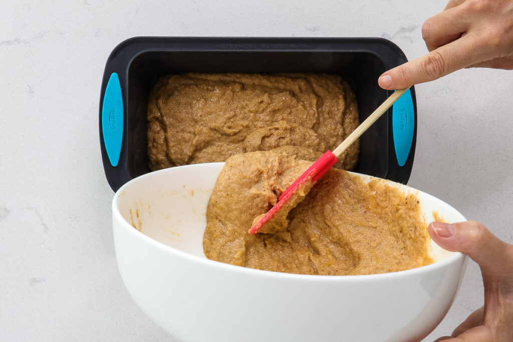 pouring cake batter into a silicone loaf pan. 