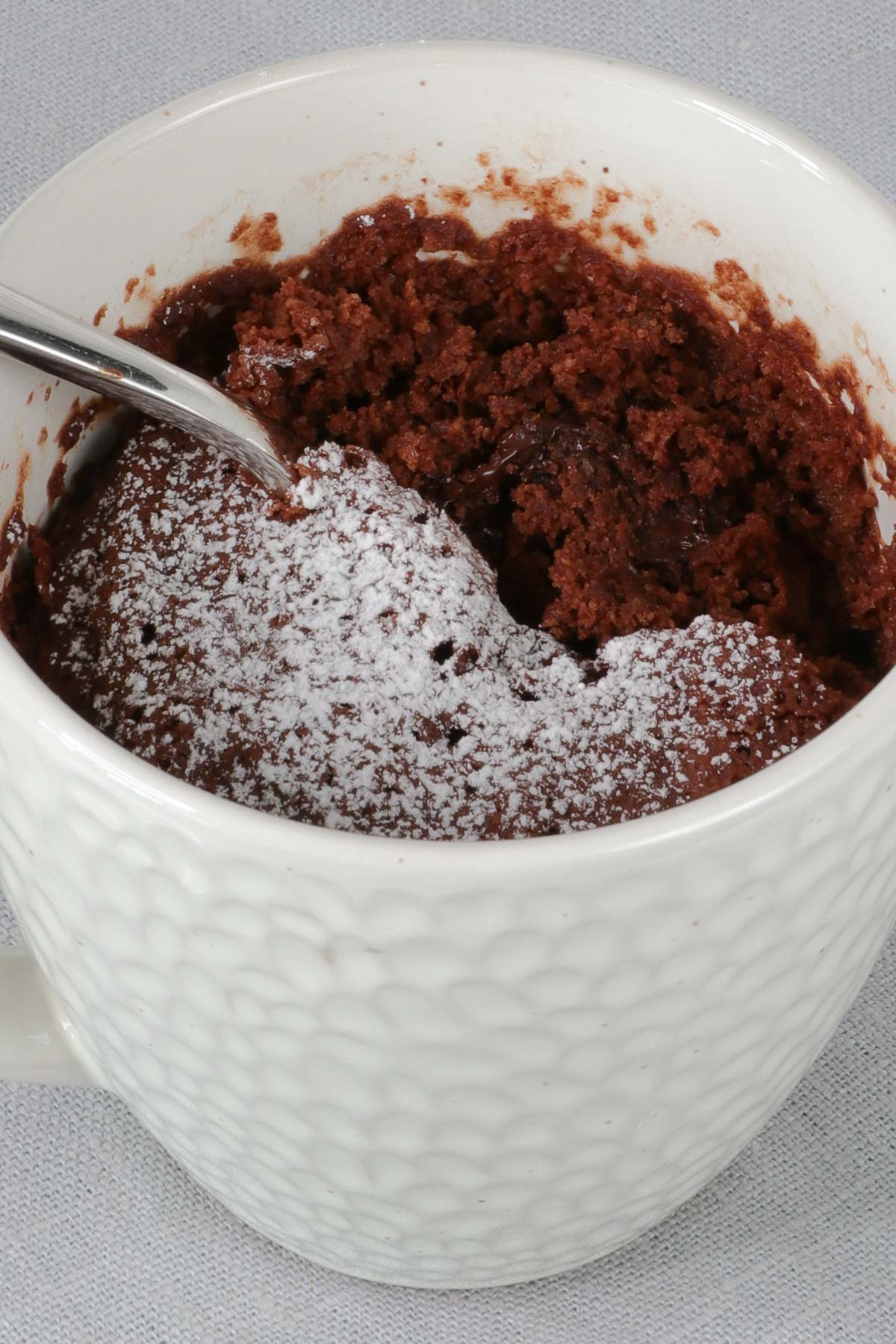 Close up of mug cake with powdered sugar topping. 