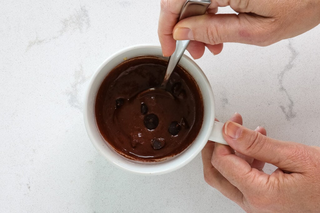 Stirring wet ingredients and chocolate chips with a spoon. 