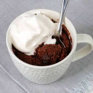 almond flour mug cake with spoon and whipped topping.