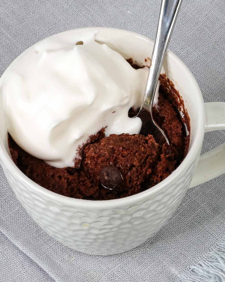 almond flour mug cake with spoon and whipped topping.