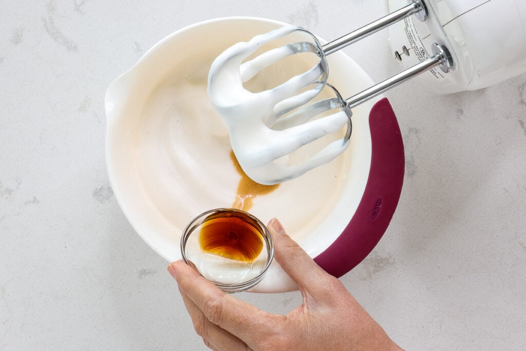 Pouring vanilla from a glass dish into a bowl of topping. 